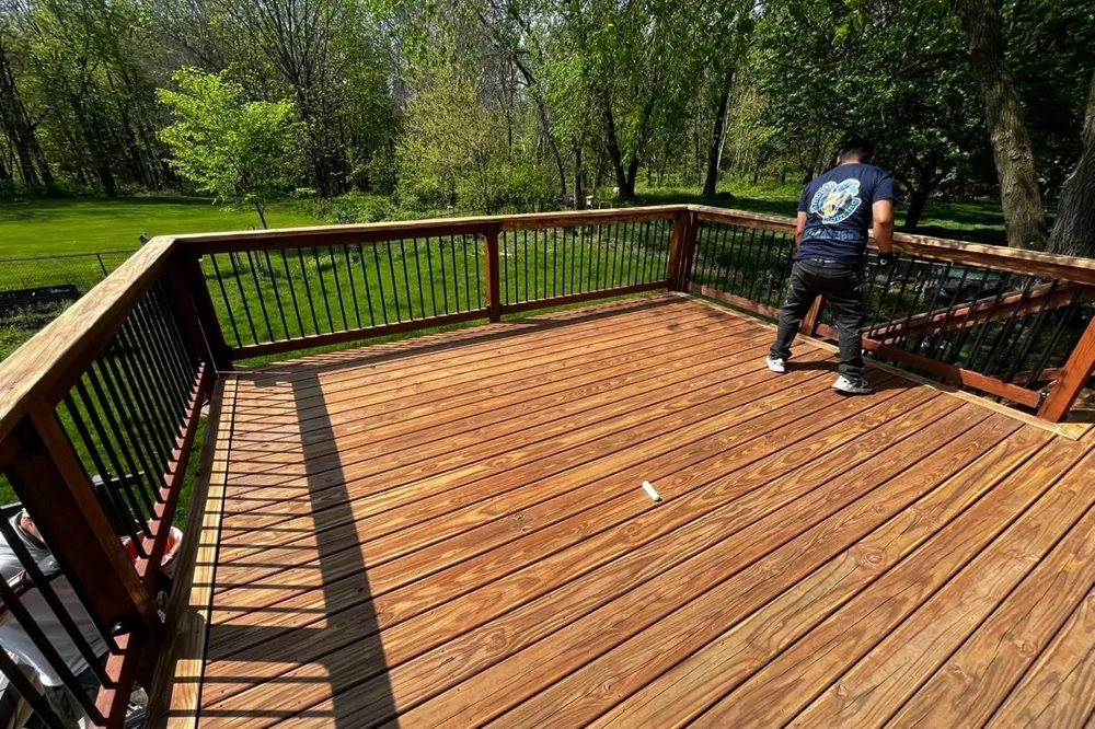Smooth Painting crew member staining a wood deck railing and floor